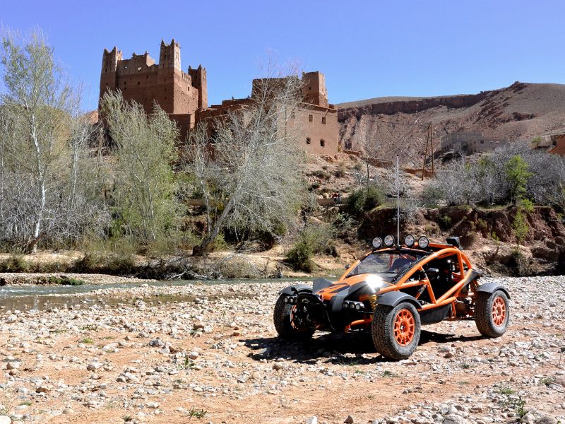 orange and black Ariel Nomad in a dried up river bed with a castle in the background
