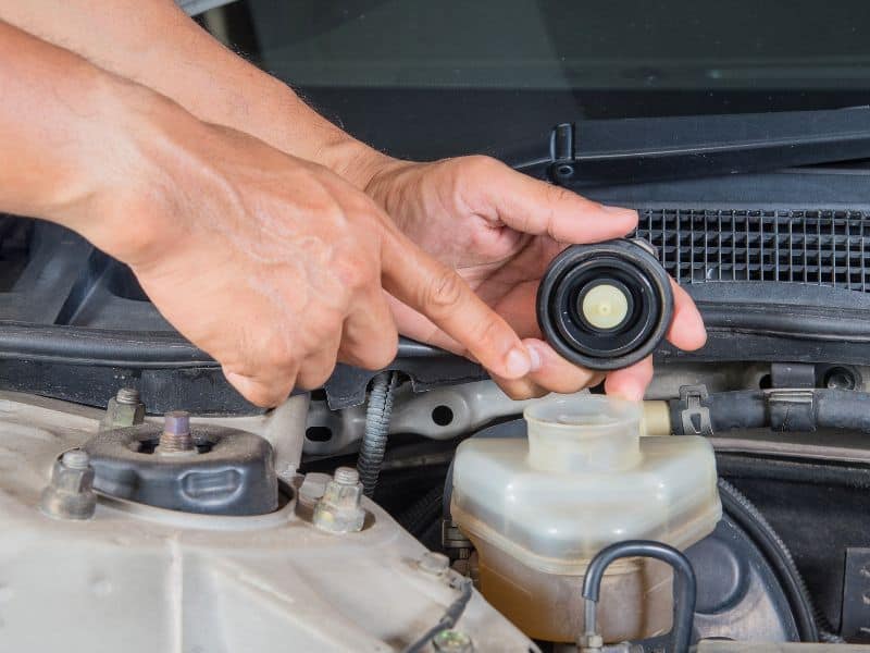 a man pointing at the fill neck of a brake fluid reservoir